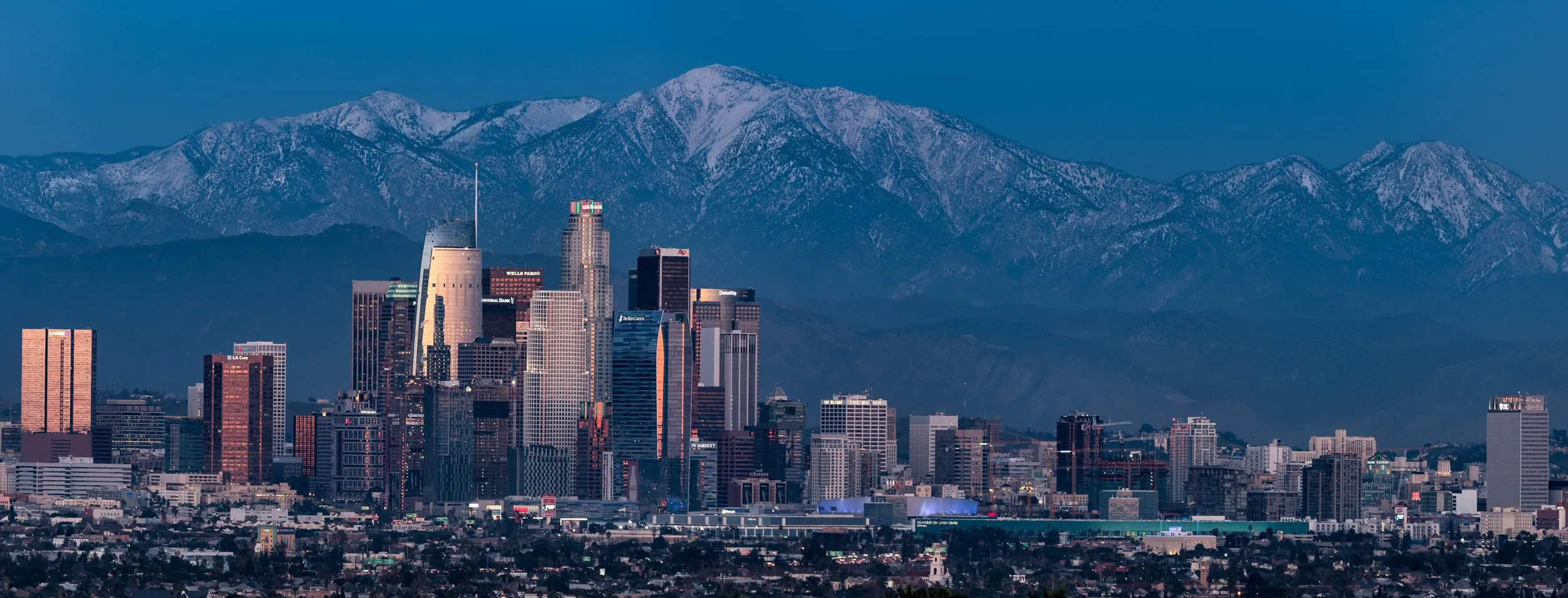 Downtown Los Angeles skyline at dusk beneath snow-capped mountains — limited edition fine art photograph by Tom Haberman